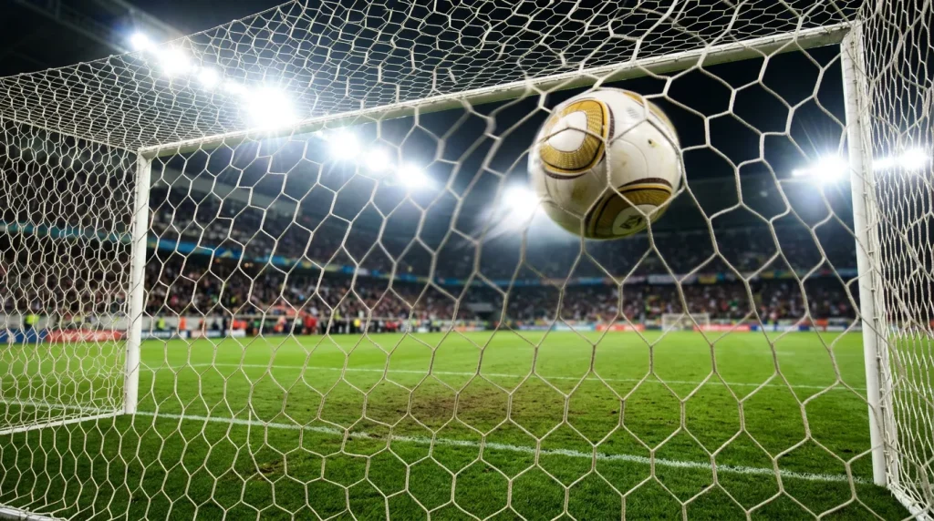 Attaquant célébrant un but devant les filets lors d'un match de football international